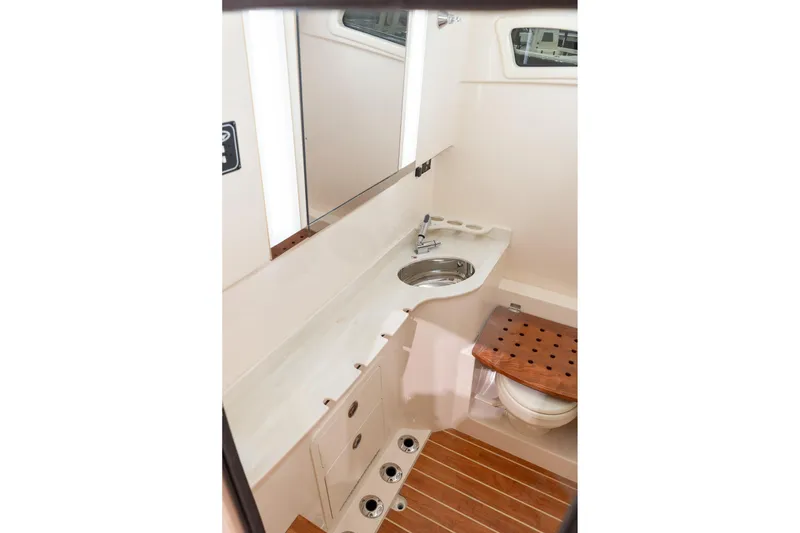 Slide: The Image of 2026 Grady-White Canyon 326 boat interior with sink, mirror, and wooden accents. - 23