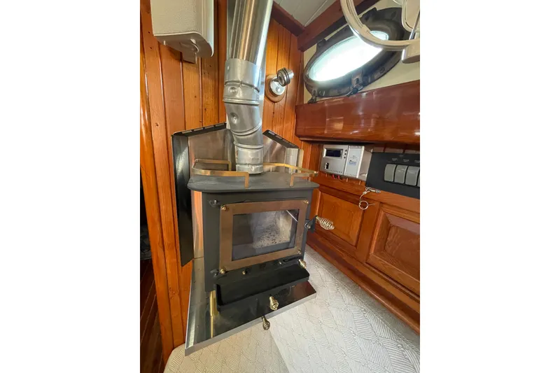 Slide: The Image of Wood stove inside 1981 Hans Christian MKII sailboat, featuring wooden interior and porthole window. - 5