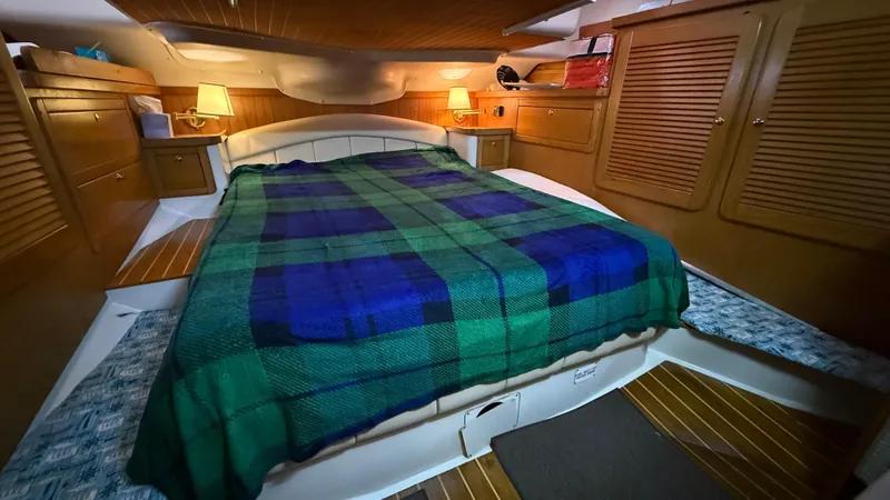 Slide: The Image of Cozy cabin interior of 2004 Catalina 470 yacht with plaid bedding and warm lighting. - 10