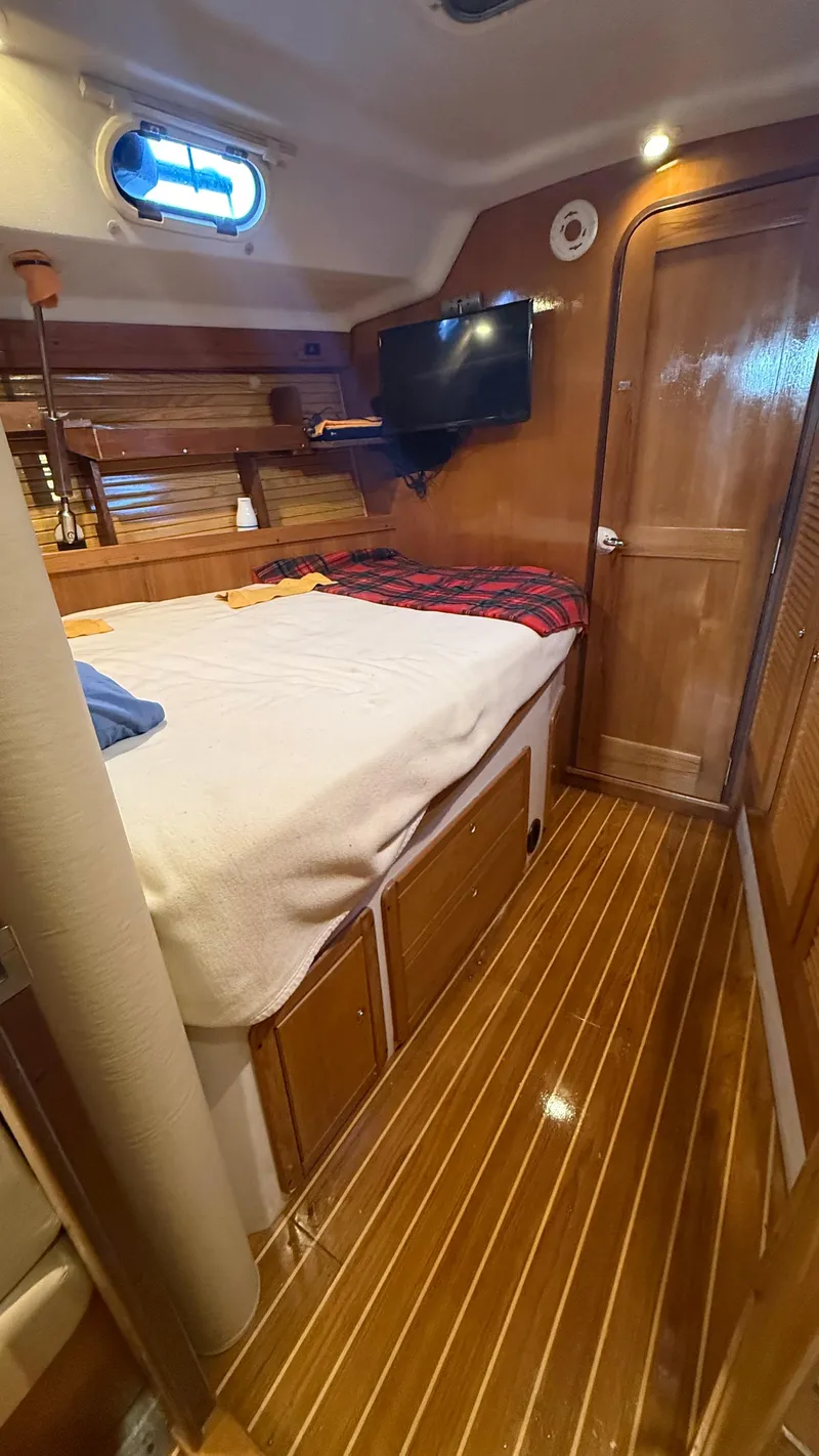 Slide: The Image of Catalina 470 yacht interior, 2004 model, featuring a cozy cabin with wood paneling and a bed. - 11