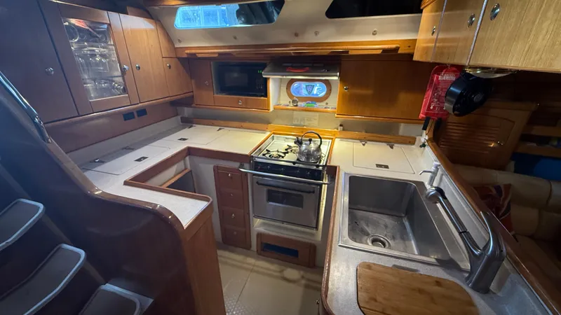 Slide: The Image of Galley kitchen in 2004 Catalina 470 yacht with stove, sink, and wooden cabinetry. - 14