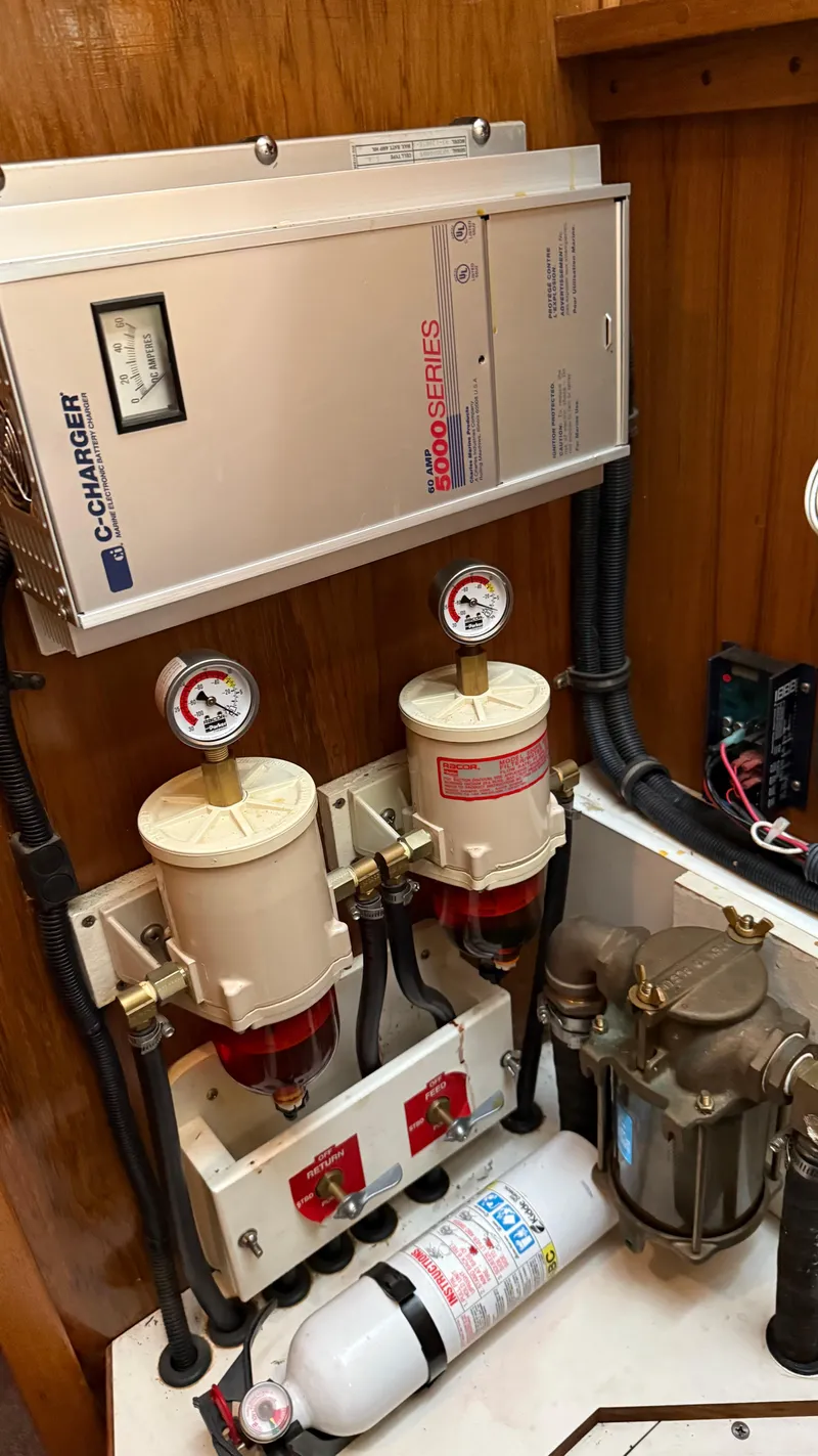 Slide: The Image of Catalina 470 yacht engine room with fuel filters, battery charger, and fire extinguisher, 2004 model. - 26