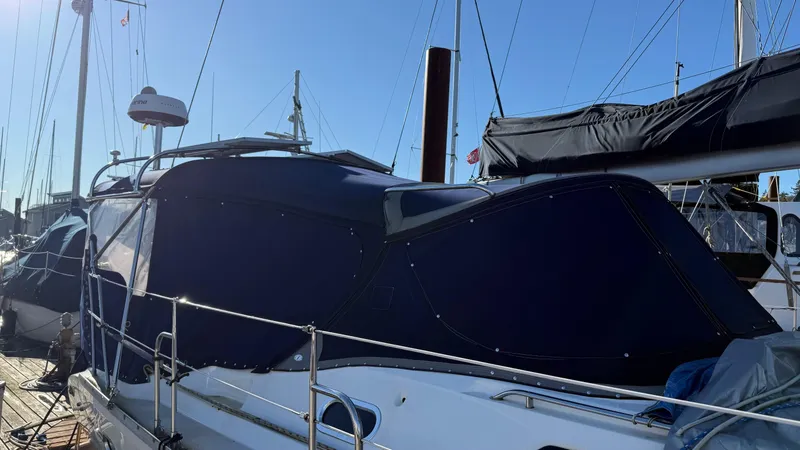 Slide: The Image of 2004 Catalina 470 sailboat docked with blue canvas cover under clear sky. - 30