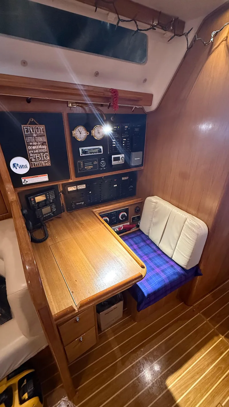 Slide: The Image of Navigation station inside 2004 Catalina 470 sailboat, featuring wooden desk and control panels. - 8