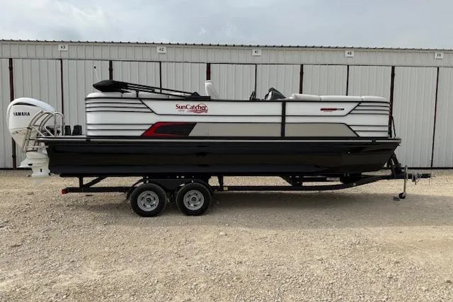 The Image of 2025 SunCatcher ELITE 324RC pontoon boat on trailer, parked outdoors. - 1