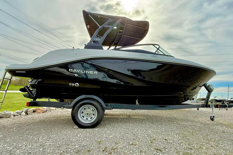 The Image of 2026 Bayliner V20i boat on trailer, sleek black design under cloudy sky. - 1