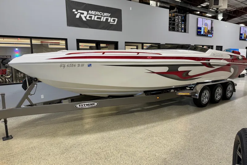 The Image of 2004 Sleekcraft Enforcer 30 boat on trailer, featuring red and black graphics, indoors. - 0