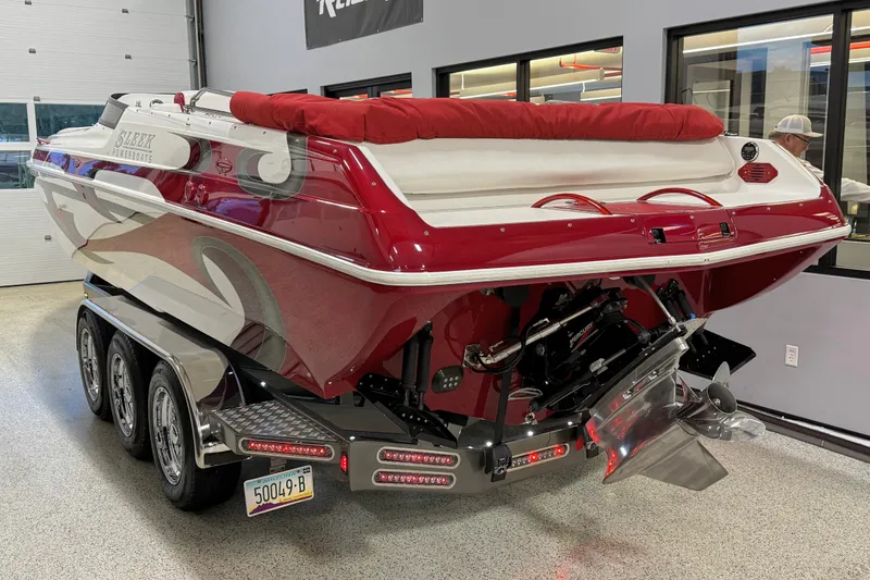 Slide: The Image of 2004 Sleekcraft Enforcer 30 boat with red and white design on a trailer indoors. - 3