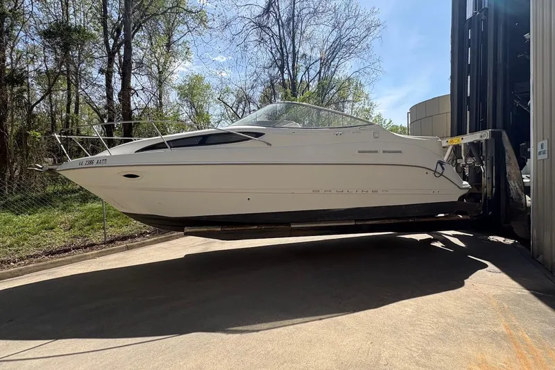 Slide: The Image of 2001 Bayliner 2655 Ciera boat on forklift, surrounded by trees and clear sky. - 2