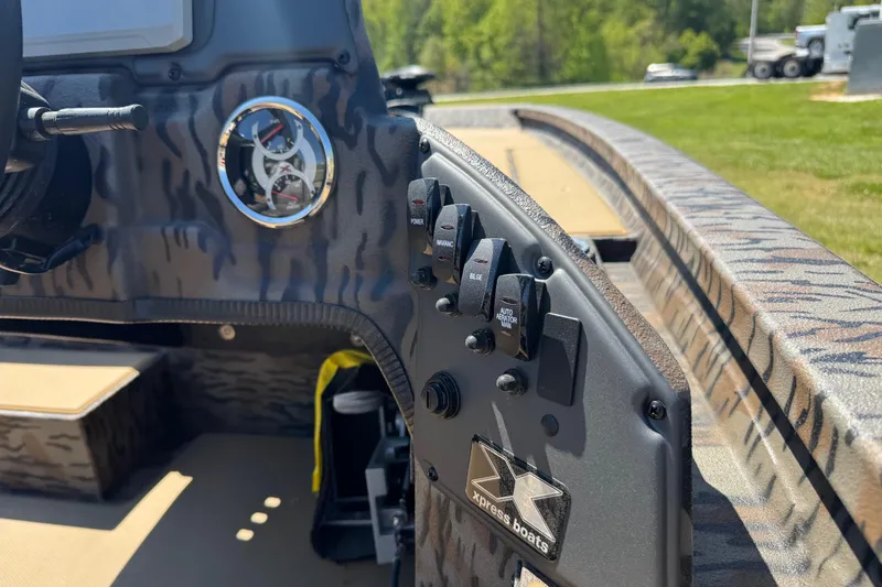 Slide: The Image of 2026 Xpress H20 Bass boat dashboard with controls and gauge, featuring camo design. - 13