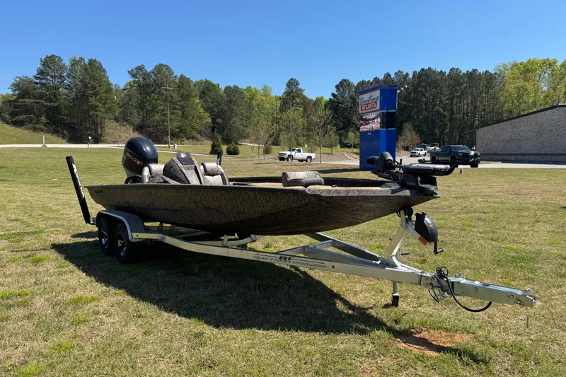Slide: The Image of 2026 Xpress H20 Bass boat on trailer, parked on grass with trees in background. - 14