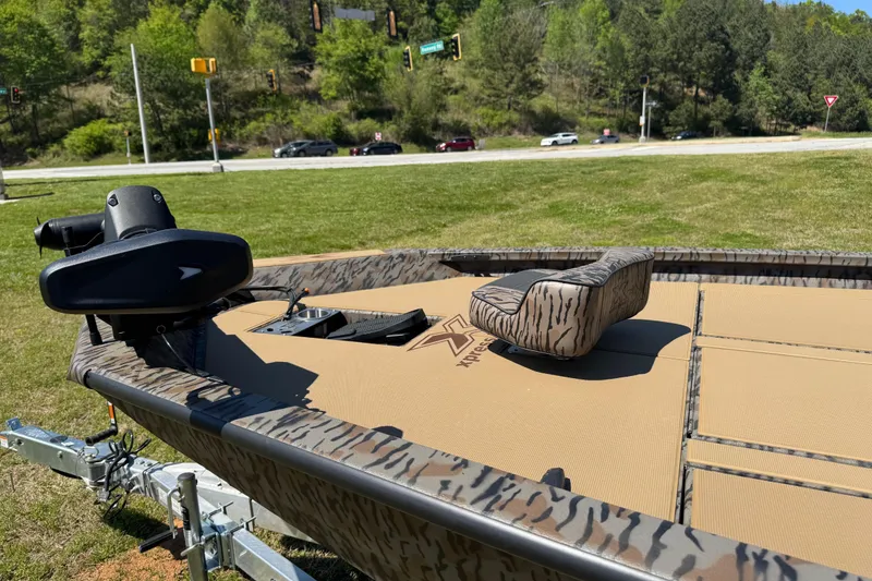 Slide: The Image of 2026 Xpress H20 Bass boat with camouflage design on a trailer, parked on grass. - 4