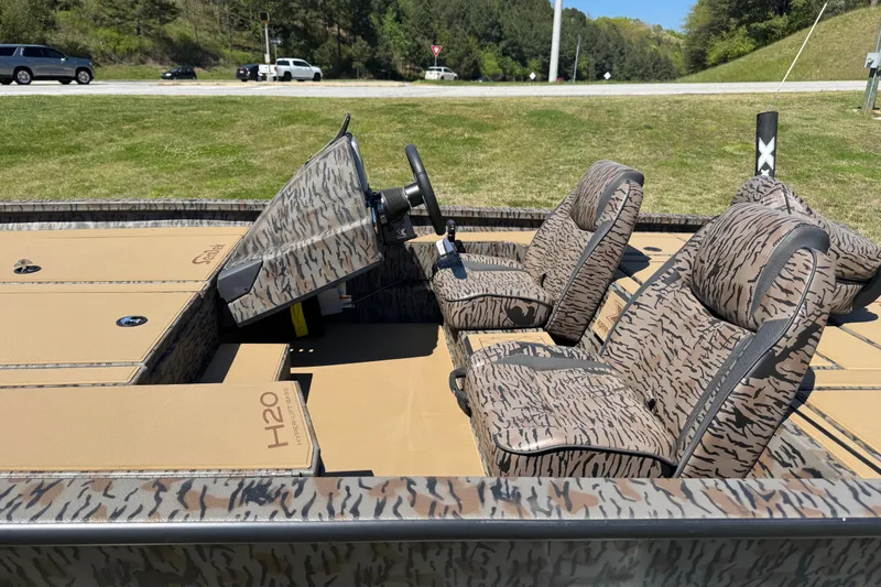 Slide: The Image of 2026 Xpress H20 Bass boat interior with camouflage seating and steering console. - 6
