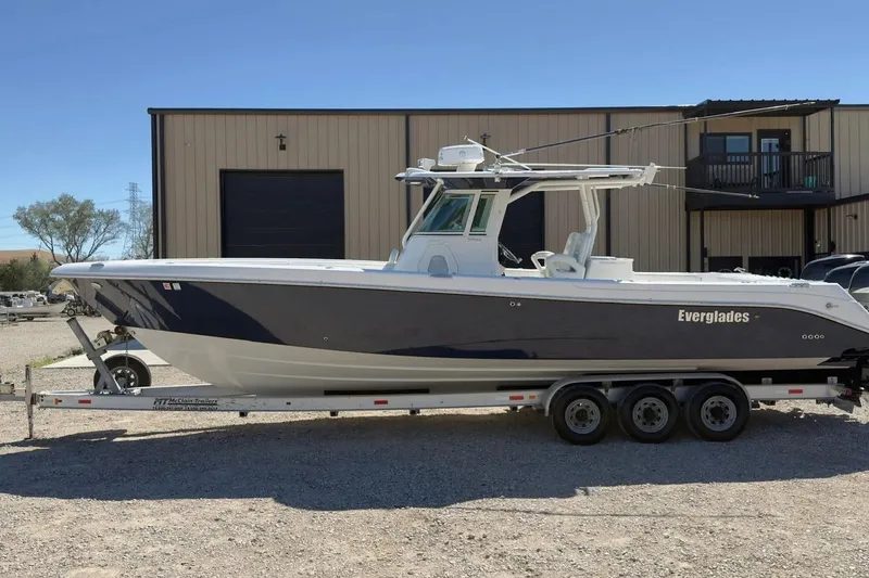 The Image of 2007 Everglades 350 Center Console boat on trailer, parked outside a building. - 1