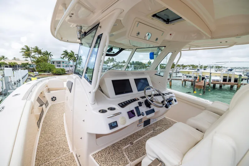 Slide: The Image of 2021 Grady-White Canyon 376 boat interior with helm, screens, and seating at marina. - 17