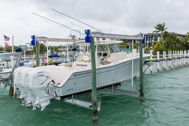 Slide: The Image of 2021 Grady-White Canyon 376 boat on lift, docked in marina with Yamaha engines. - 2