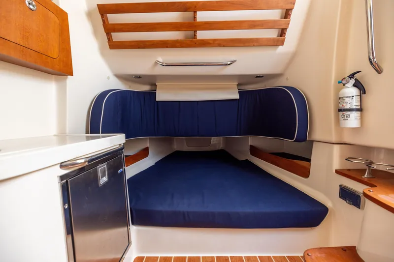Slide: The Image of 2021 Grady-White Canyon 376 cabin interior with blue bedding and wooden accents. - 35
