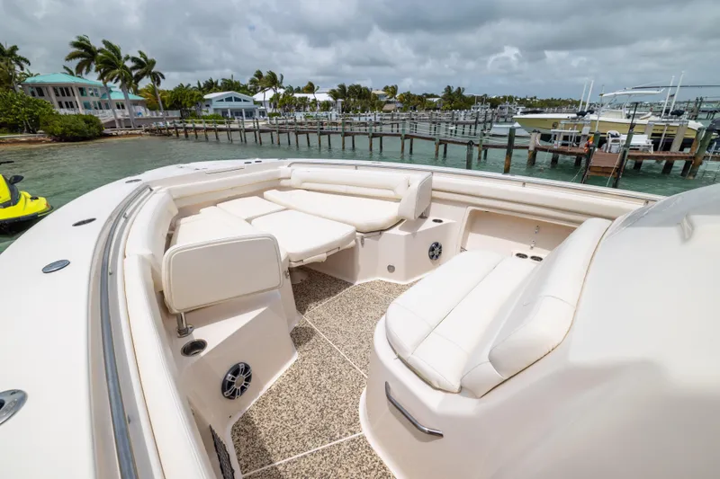 Slide: The Image of 2021 Grady-White Canyon 376 boat interior with plush seating, docked near tropical waterfront homes. - 8