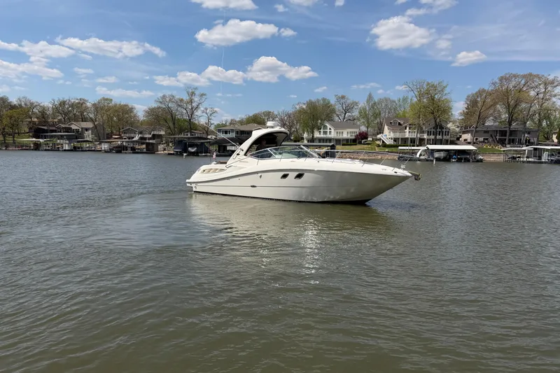 Slide: The Image of 2008 Sea Ray Sundancer 330 yacht on a serene lake with waterfront homes in the background. - 2