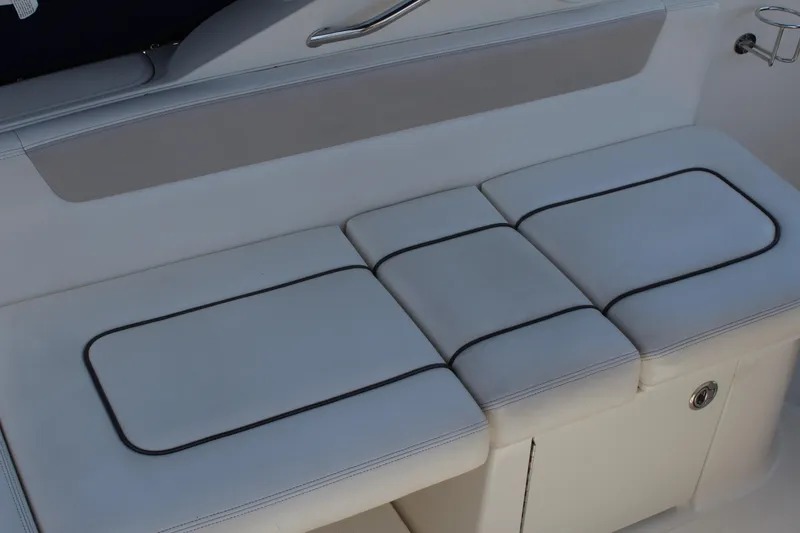 Slide: The Image of White cushioned seating on 2011 Sea Ray Sundancer 260 boat, featuring sleek design and storage. - 12