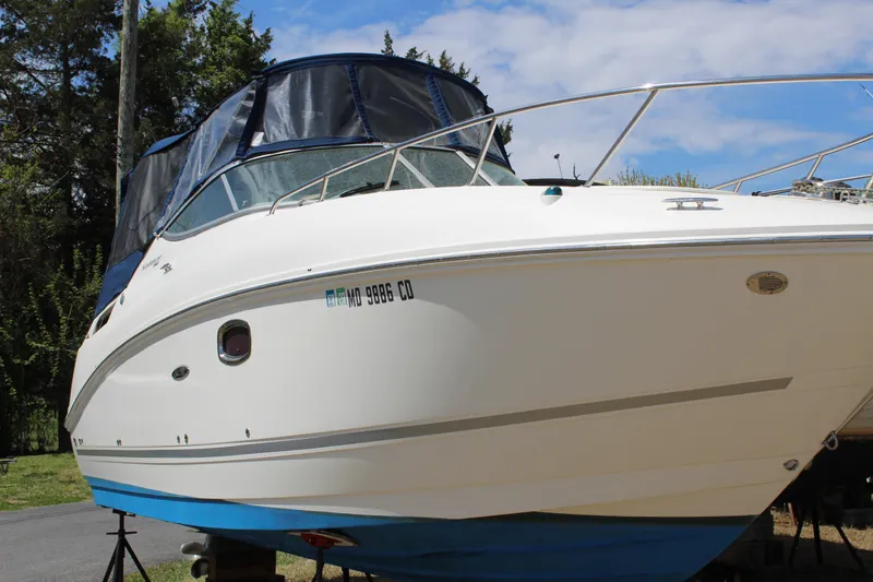 Slide: The Image of 2011 Sea Ray Sundancer 260 boat on land, blue hull, covered cockpit. - 8
