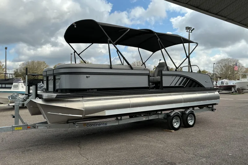 Slide: The Image of 2026 Qwest L-Class Splash Pad 24 pontoon boat on trailer, under cloudy sky. - 5