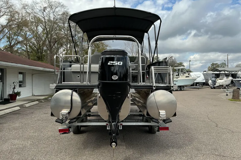 Slide: The Image of 2026 Qwest L-Class Splash Pad 24 pontoon boat with 250 HP engine, parked outdoors. - 7