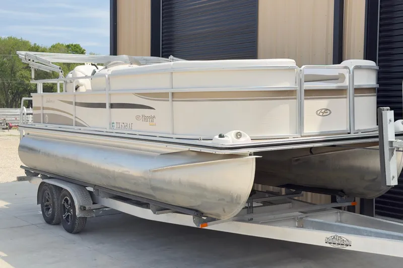 Slide: The Image of 2007 Harris Sunliner 220 pontoon boat on trailer, parked near a building. - 2