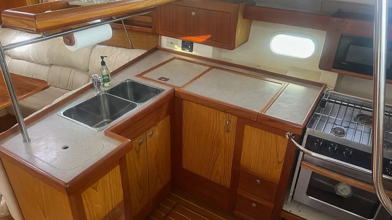 Slide: The Image of Hunter 410 yacht kitchen interior with wooden cabinets, dual sink, and stove, year 2000 model. - 10