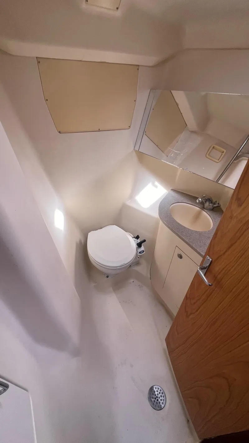Slide: The Image of Compact bathroom in a 2000 Hunter 410 boat, featuring a toilet, sink, and mirror. - 22