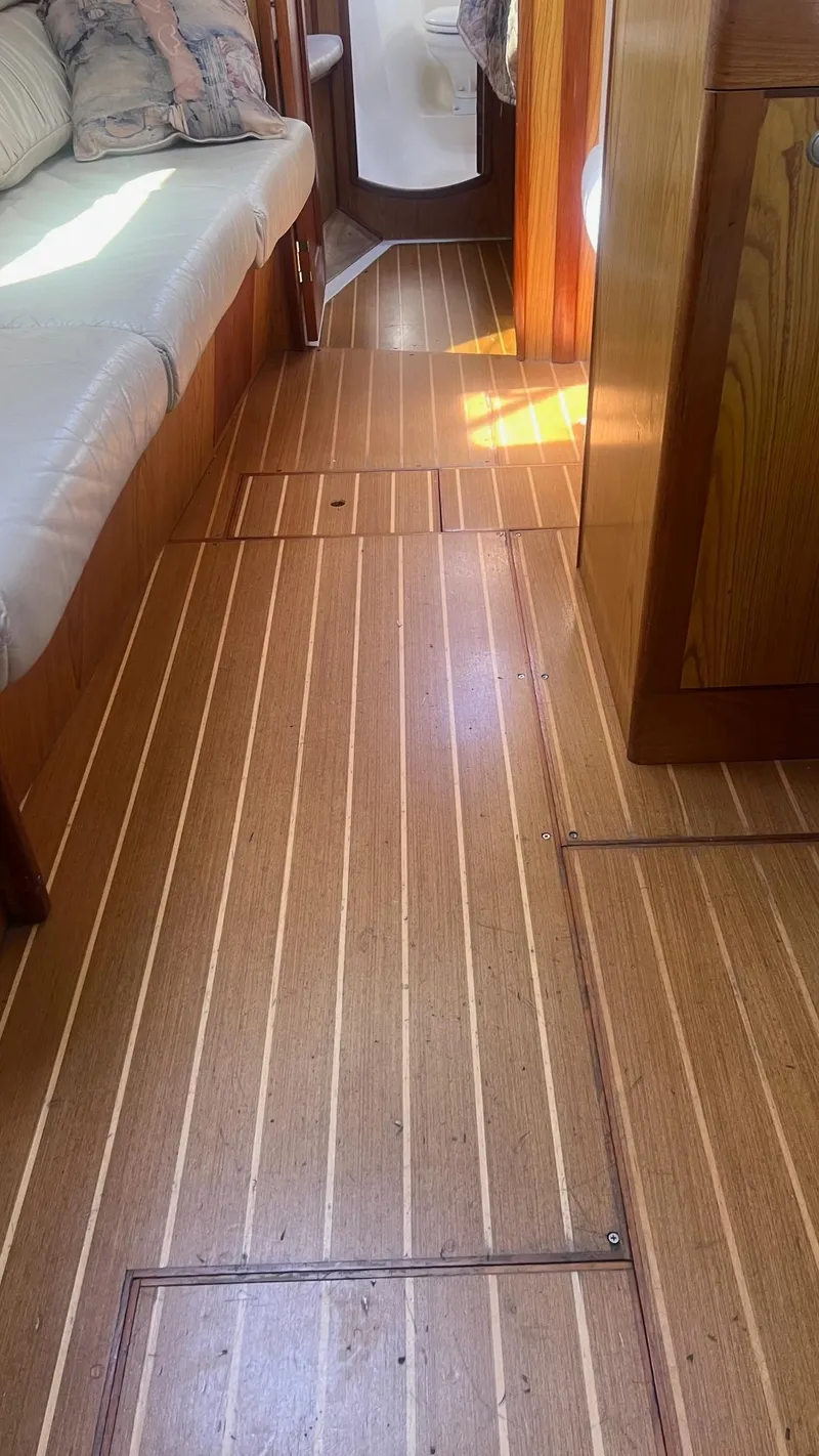 Slide: The Image of Interior of 2000 Hunter 410 sailboat with wooden flooring and cushioned seating. - 29