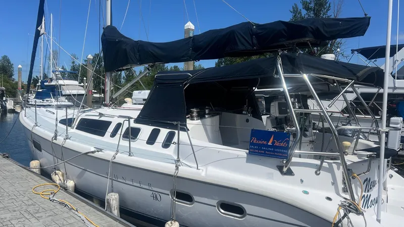 Slide: The Image of 2000 Hunter 410 sailboat docked at marina, featuring sleek design and covered cockpit. - 35