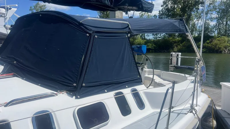 Slide: The Image of 2000 Hunter 410 sailboat with blue canopy docked by a serene river. - 37