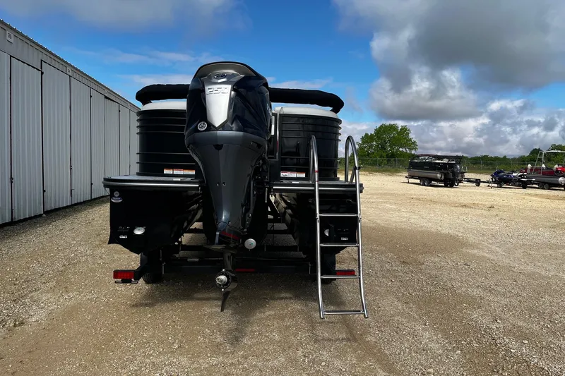 Slide: The Image of 2025 SunCatcher ELITE 324RC pontoon boat with outboard motor and ladder, parked outdoors. - 7