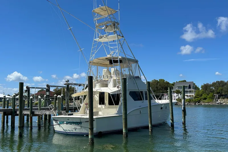 Slide: The Image of 1989 Hatteras 45 Convertible yacht docked in a serene marina under a clear blue sky. - 2
