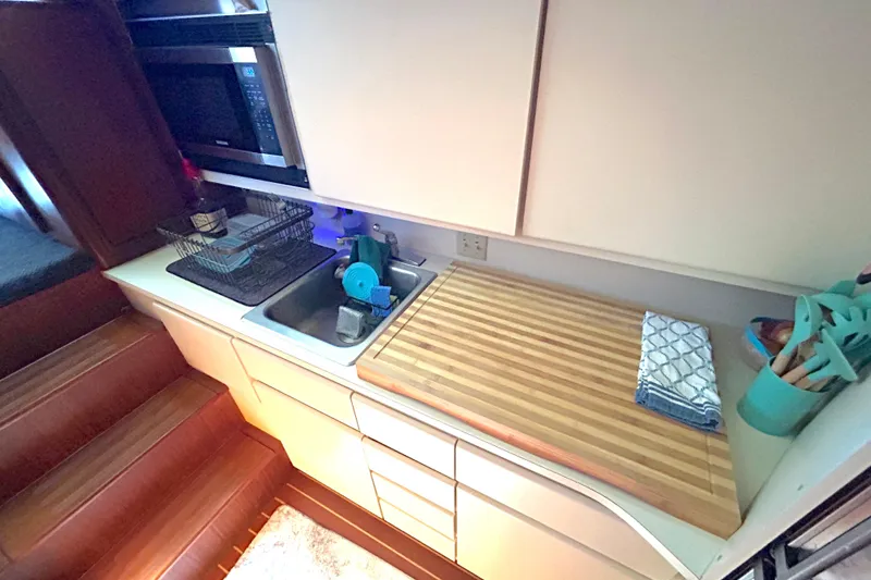 Slide: The Image of Compact kitchen area in a 1989 Hatteras 45 Convertible yacht, featuring sink and cutting board. - 23