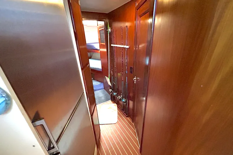 Slide: The Image of Interior hallway of 1989 Hatteras 45 Convertible yacht with wooden paneling and fishing rods. - 26