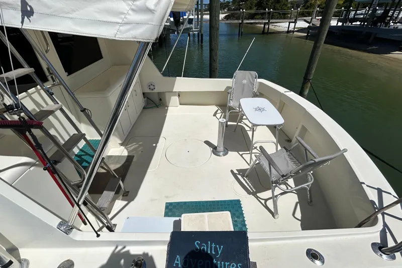 Slide: The Image of 1989 Hatteras 45 Convertible yacht deck with chairs and table, docked by water. - 3