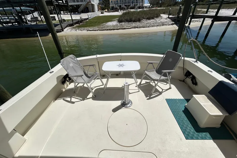 Slide: The Image of 1989 Hatteras 45 Convertible boat deck with chairs and table, docked by the water. - 9