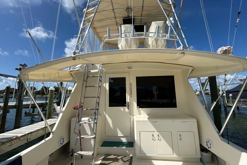 Slide: The Image of 1989 Hatteras 45 Convertible yacht at dock, featuring ladder and upper deck. - 5