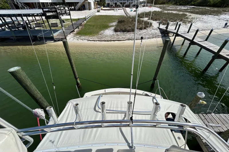 Slide: The Image of 1989 Hatteras 45 Convertible yacht docked near sandy shoreline and wooden pier. - 57