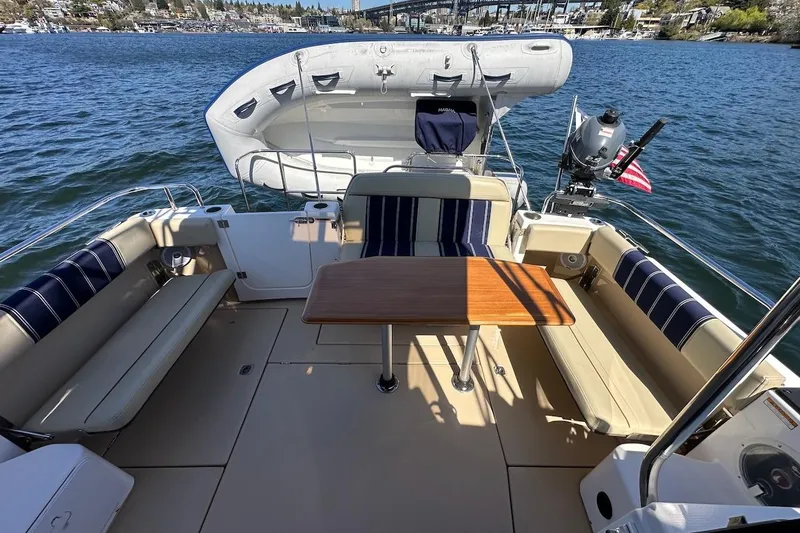 Slide: The Image of 2018 Ranger Tugs R-29 CB boat deck with seating, table, and inflatable dinghy on water. - 12