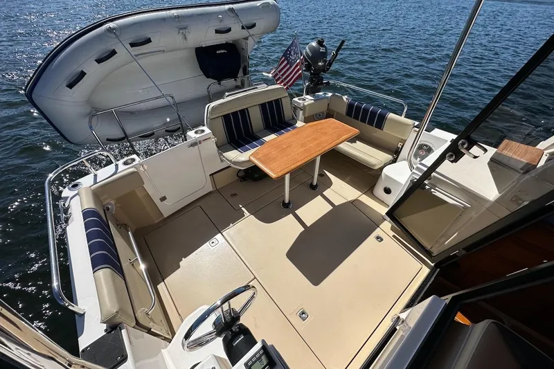 Slide: The Image of 2018 Ranger Tugs R-29 CB boat deck with seating, table, and American flag. - 14