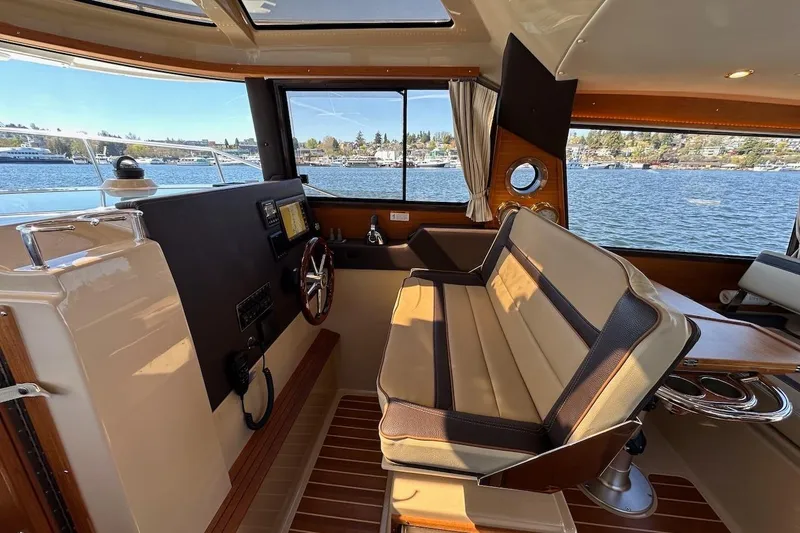 Slide: The Image of 2018 Ranger Tugs R-29 CB interior with helm, seating, and scenic water view. - 35