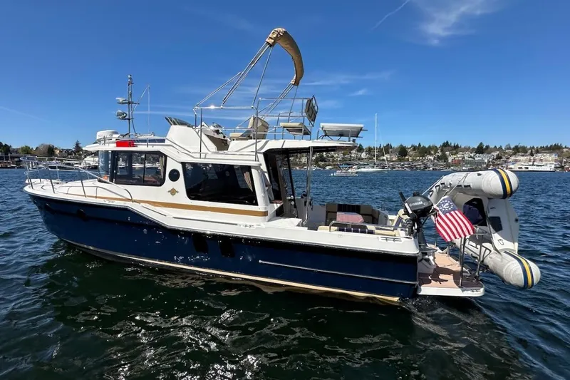Slide: The Image of 2018 Ranger Tugs R-29 CB boat on water with American flag and inflatable dinghy. - 6