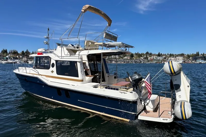 Slide: The Image of 2018 Ranger Tugs R-29 CB boat on water, featuring a spacious deck and flybridge. - 7