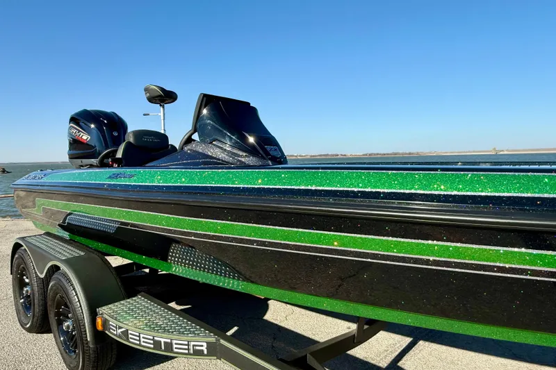 Slide: The Image of 2022 Skeeter ZX225 boat with green and black design on a trailer by the water. - 14
