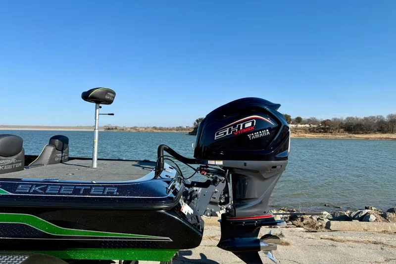 Slide: The Image of 2022 Skeeter ZX225 boat with Yamaha engine by a lake under clear blue sky. - 2
