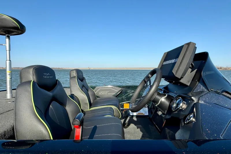 Slide: The Image of 2022 Skeeter ZX225 boat interior with steering wheel and seats, overlooking a calm lake. - 4