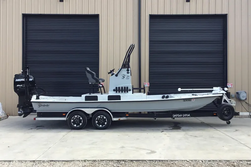 The Image of 2015 Shoalwater 23' Catamaran on trailer, parked outside a building with black shutters. - 1
